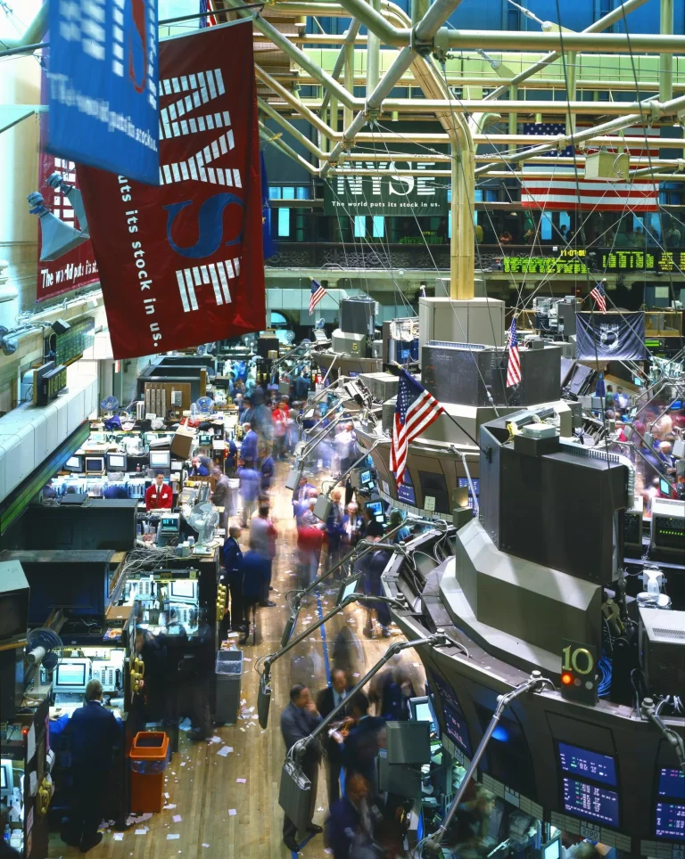Business Analysis: The Money Flowing Into AI, and the Returns Investors Expect Traders and financial data screens in a busy stock market setting