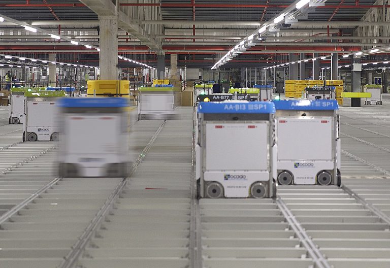 Warehouse Robotics Are Reshaping Logistics Work From the Inside Orange mobile robots moving shelves in a large automated warehouse